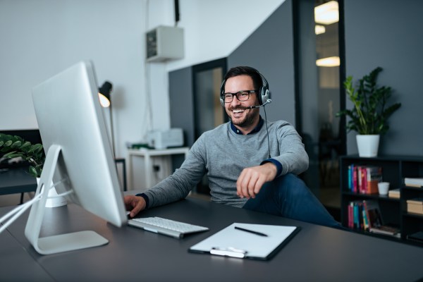 Guapo hombre de negocios casual hablando en línea a través de auriculares.